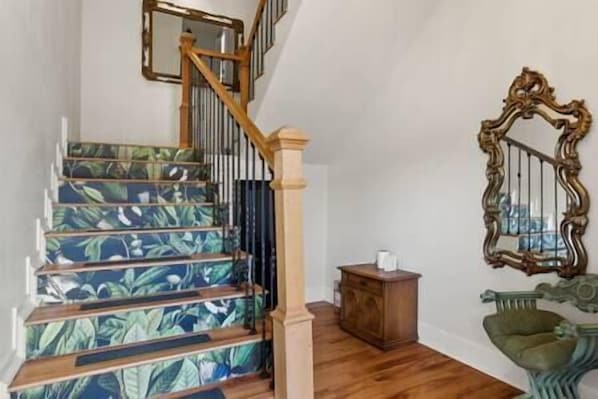A staircase with a floral pattern, a wooden handrail, and a mirror on the wall.