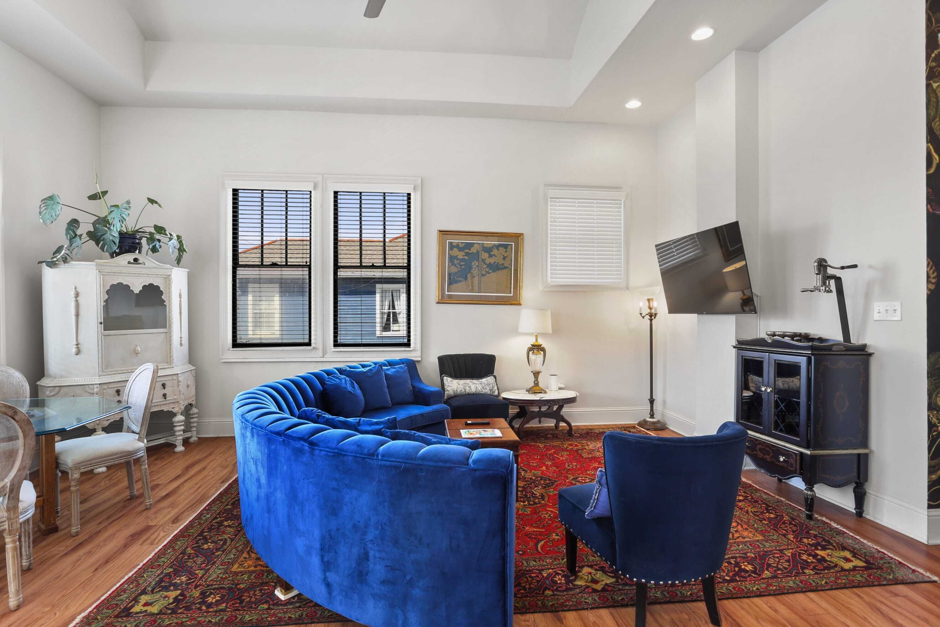 A living room with a blue sofa, a small table, a chair, a cabinet, and a TV.