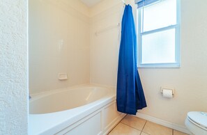 Bathroom features a bathtub, shower area, and toilet, with a window for natural light.