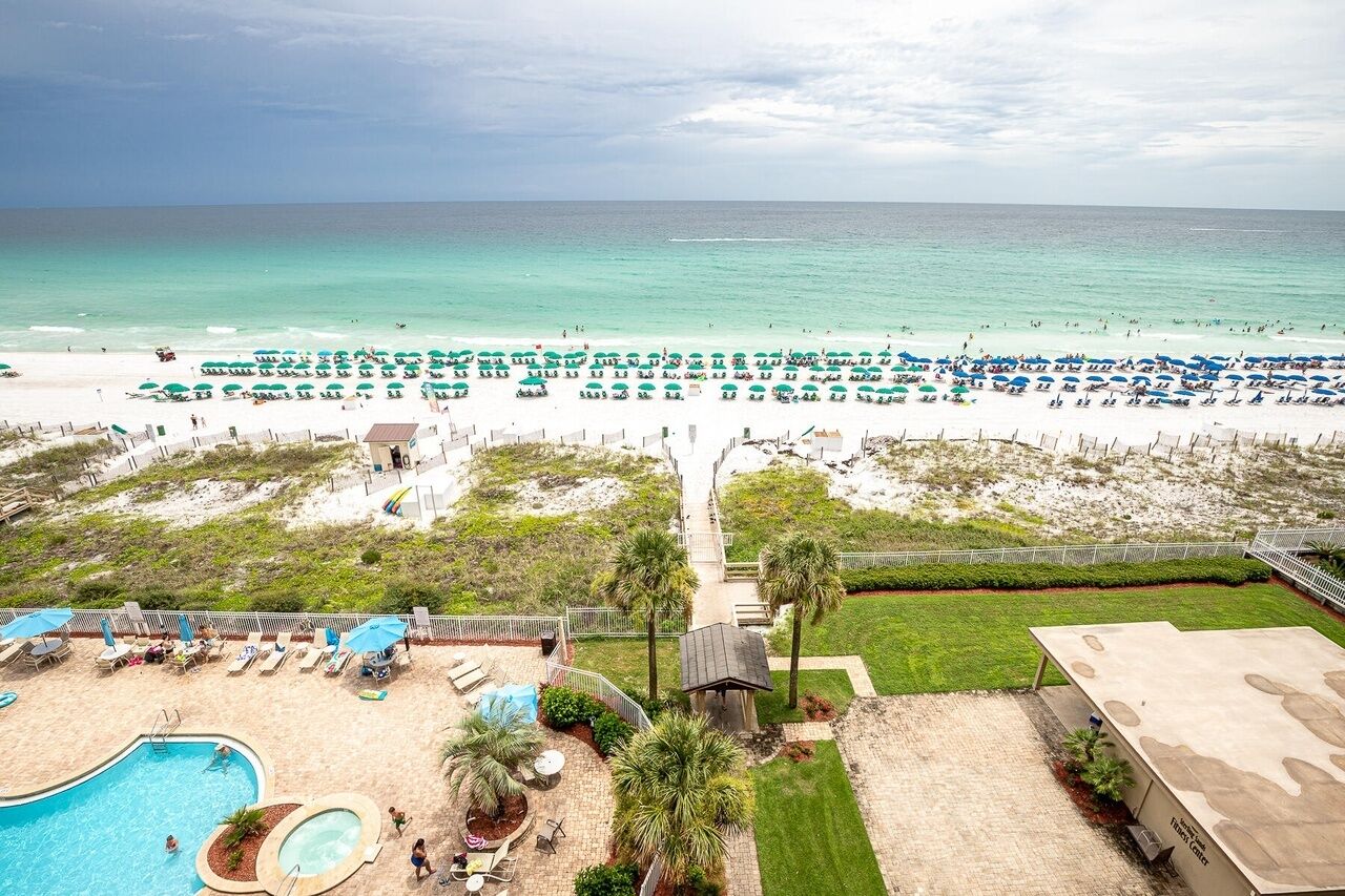 A beach resort with a swimming pool, lounge chairs, and a view of the ocean.