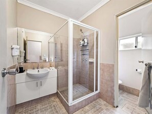 Un baño con ducha de vidrio, lavamanos e inodoro.