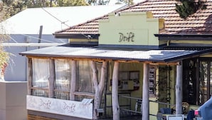 A cafe named Drift with a rustic exterior, wooden slats, and a sign indicating it's open.