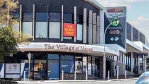 A modern building with a sign for 'The Village at Marks' and a Woolworths store.