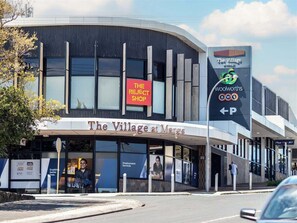 Un bâtiment moderne avec une enseigne indiquant « The Village at Marks » et un magasin Woolworths.
