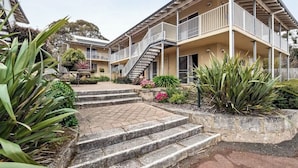 A residential building with a central staircase, balconies, and surrounding vegetation.