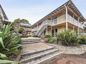 A residential building with a central staircase, balconies, and surrounding vegetation.