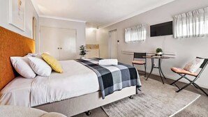 A hotel room with a bed, a desk, a chair, and a television.