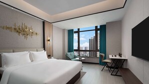 Una habitación de hotel moderna con una cama grande, un escritorio y vistas a la ciudad.
