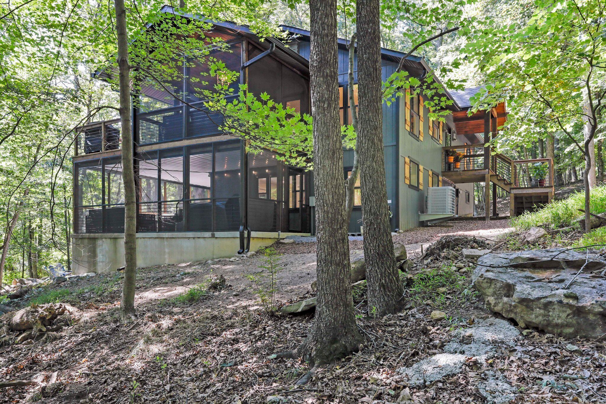 A modern house with large windows, a deck, and a stone pathway.