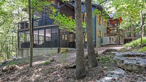 A modern house with large windows, a deck, and a stone pathway. - 🌻Have FUN in the Fall Foliage TREETOPS🍁Luxury 4 Suite Cabin🍁Screened Porches🌻 (Berkeley Springs)