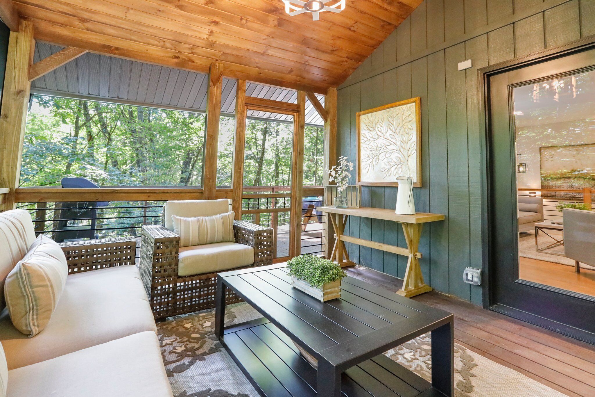 A cozy interior with a wooden ceiling, a sofa, a coffee table, and a view of the outdoors.