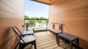 A balcony with wooden panel walls, two chairs, and a small table. - 2 King BR I Front Street + Walk DT (Traverse City)