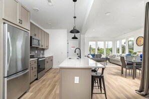 Una cocina moderna con electrodomésticos de acero inoxidable, una isla central y un comedor con sofá y sillas.