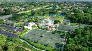 An aerial view of a residential area with multiple tennis courts, a swimming pool, and a parking lot. - Limited-Time Summer Deal on Lovely 2BR Condo with Tennis (naples)