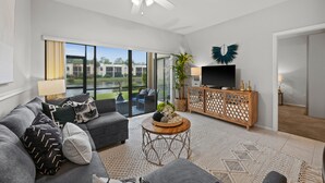 A modern living room with a grey sofa, a wooden coffee table, and a TV on a wooden cabinet. - Limited-Time Summer Deal on Lovely 2BR Condo with Tennis (naples)
