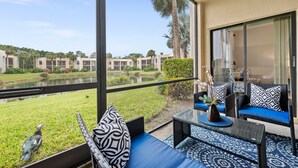 A balcony with outdoor seating, a view of a pond, and a building complex in the background. - Limited-Time Summer Deal on Lovely 2BR Condo with Tennis (naples)
