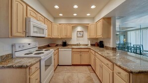 Una cocina con armarios de madera, estufa blanca, microondas y lavavajillas.