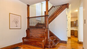 A wooden staircase with a metal railing, a framed picture on the wall, and a kitchen area in the background. - Huge 6Bd House Historic Updated King Bed Shaw (St. Louis)