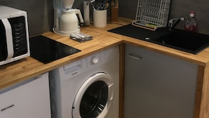 A compact kitchen with a washing machine, a microwave, and a coffee maker. - Coquet Studio CDG , Parc Astérix (Coye-la-Forêt)