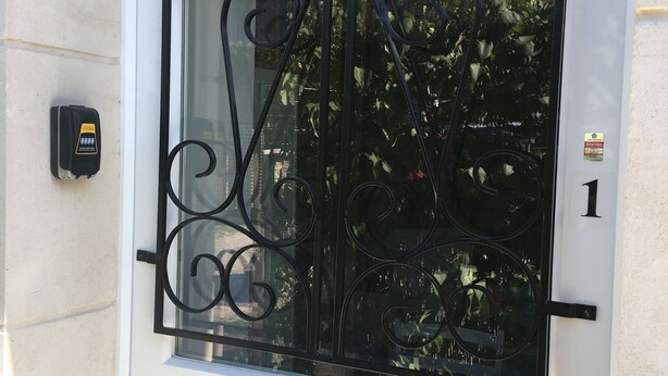 A white door with a black metal gate and a keyhole. - Coquet Studio CDG , Parc Astérix (Coye-la-Forêt)
