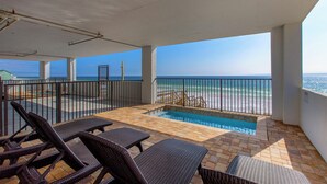 Un espacio exterior techado con piscina, sillas de descanso y vista a la playa.