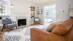 A living room with a fireplace, a sofa, two armchairs, and a bookshelf. - West Boulevard Hideway (Rapid City)
