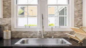 A kitchen with a stainless steel sink, a double window, and a wooden chair rack. - West Boulevard Hideway (Rapid City)