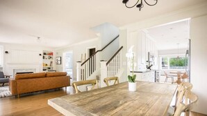A spacious living area with a wooden dining table, a sofa, and a staircase leading to an upper floor. - West Boulevard Hideway (Rapid City)