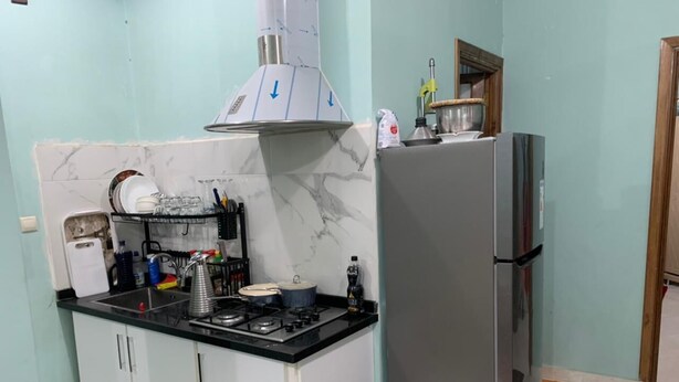 Une cuisine compacte équipée d’une cuisinière à gaz, d’un réfrigérateur en acier inoxydable et d’un dosseret en marbre.