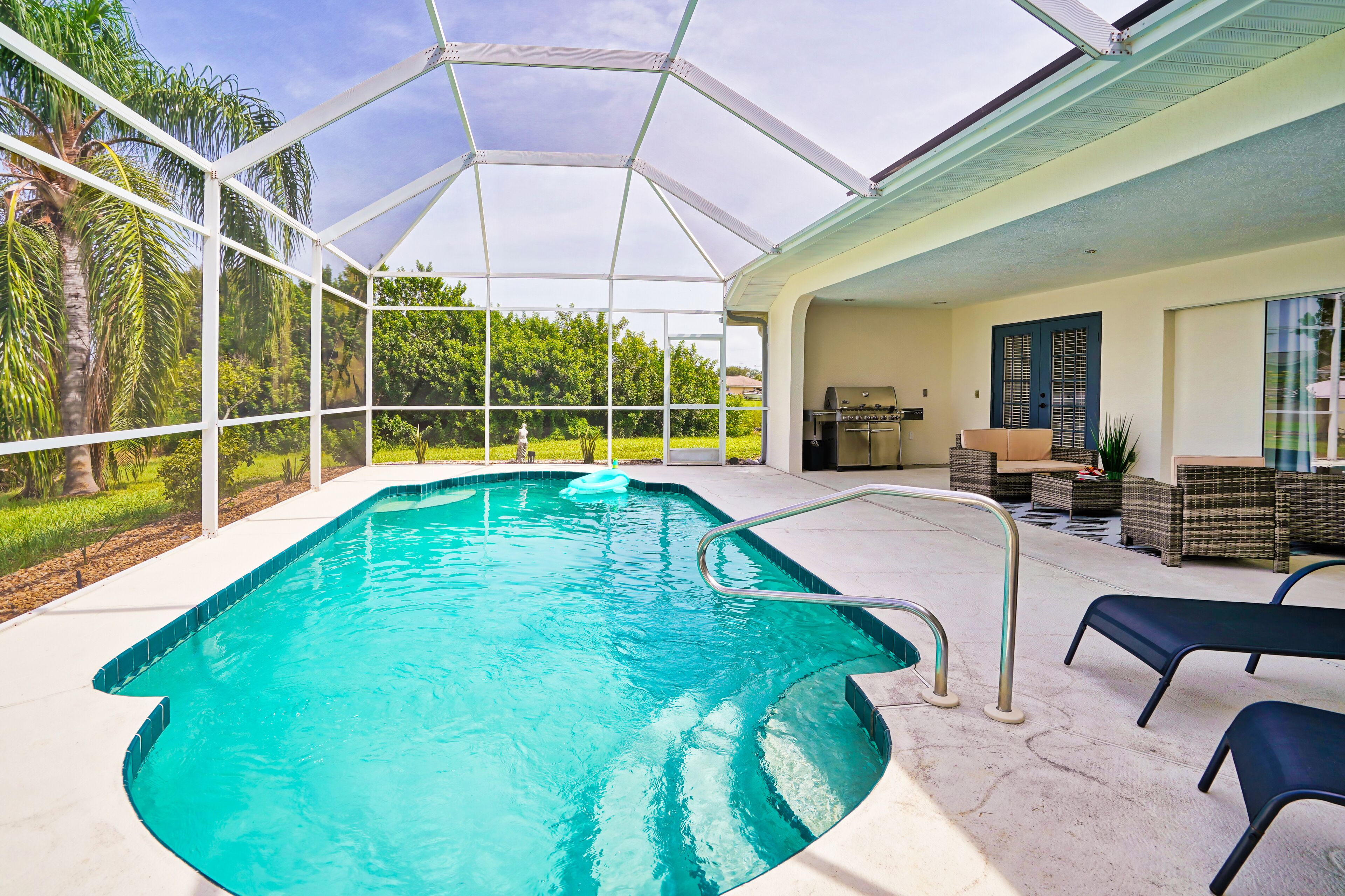 A swimming pool with a glass enclosure, surrounded by lounge chairs and a barbecue area.