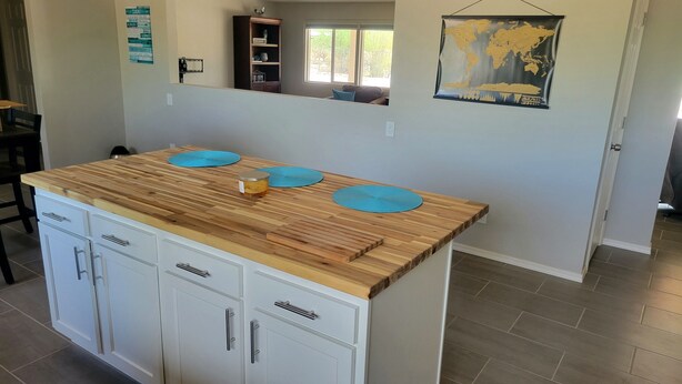 Une cuisine avec un plan de travail en bois, des armoires blanches et un tapis bleu.