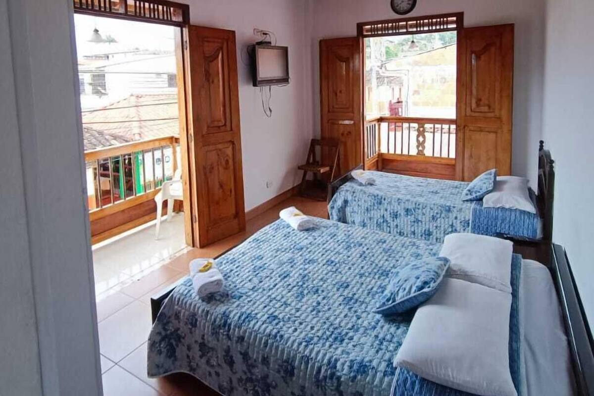 A room with two beds, wooden ceiling, and a TV on the wall.