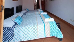 A room with a large bed, wooden ceiling beams, a painting on the wall, and a television. - Hotel Monte Verde (Salento)