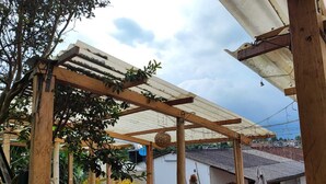 A wooden pergola structure with a roof, surrounded by potted plants and outdoor furniture. - Hotel Monte Verde (Salento)