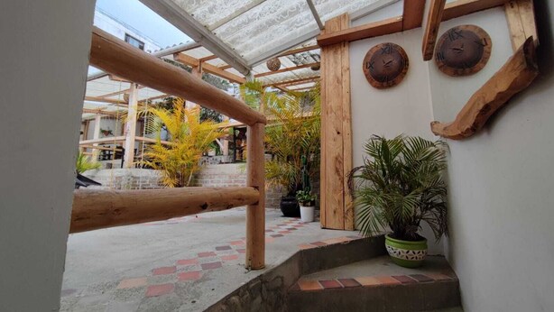A covered outdoor area with wooden beams, potted plants, and a small staircase leading to a higher level. - Hotel Monte Verde (Salento)