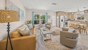 A modern living room with a sofa, coffee table, and chairs, a dining area with a table and chairs, and a kitchen with appliances and cabinets. - On Turtle Time - Beach Cottage w/ Heated Pool & Close to the Sand (Holmes Beach)