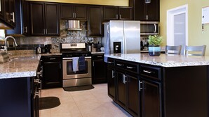 A modern kitchen with dark cabinetry, stainless steel appliances, and a granite countertop. - Spacious Buckeye Vacation Home (Buckeye)