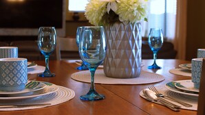 A dining table set with blue glassware, white plates, and a vase with white flowers. - Spacious Buckeye Vacation Home (Buckeye)