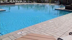 A clear blue pool with lounge chairs and umbrellas, surrounded by a brick wall and sparse vegetation. - Spacious Buckeye Vacation Home (Buckeye)
