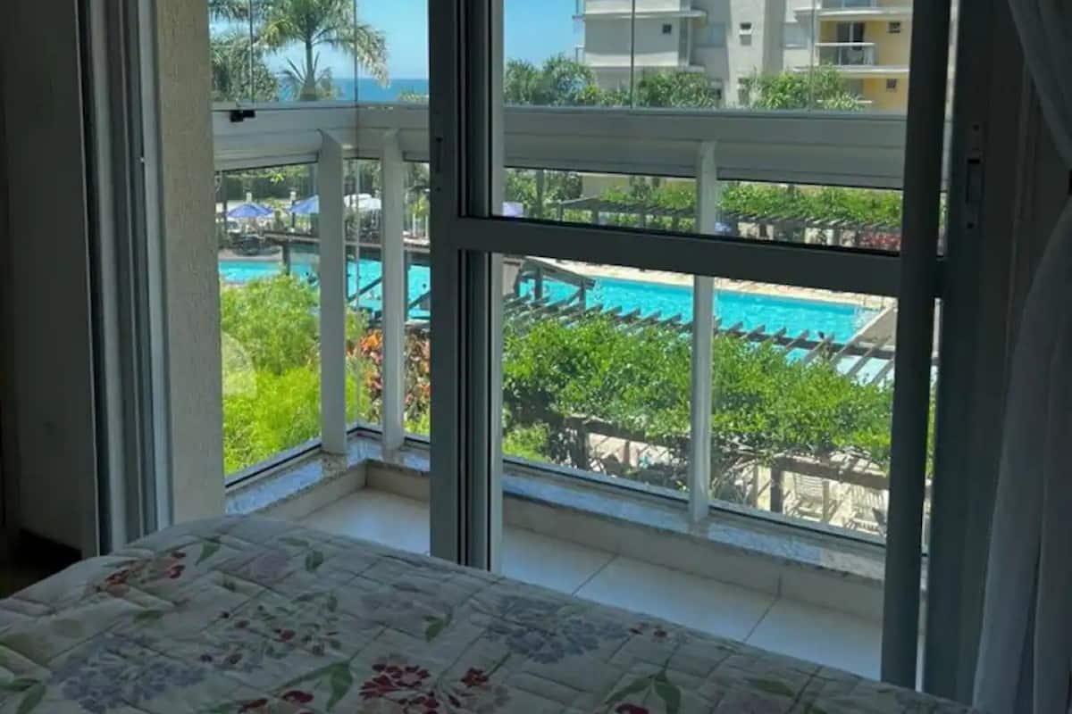 Quarto com uma grande janela com vista para uma piscina e um edifício alto.