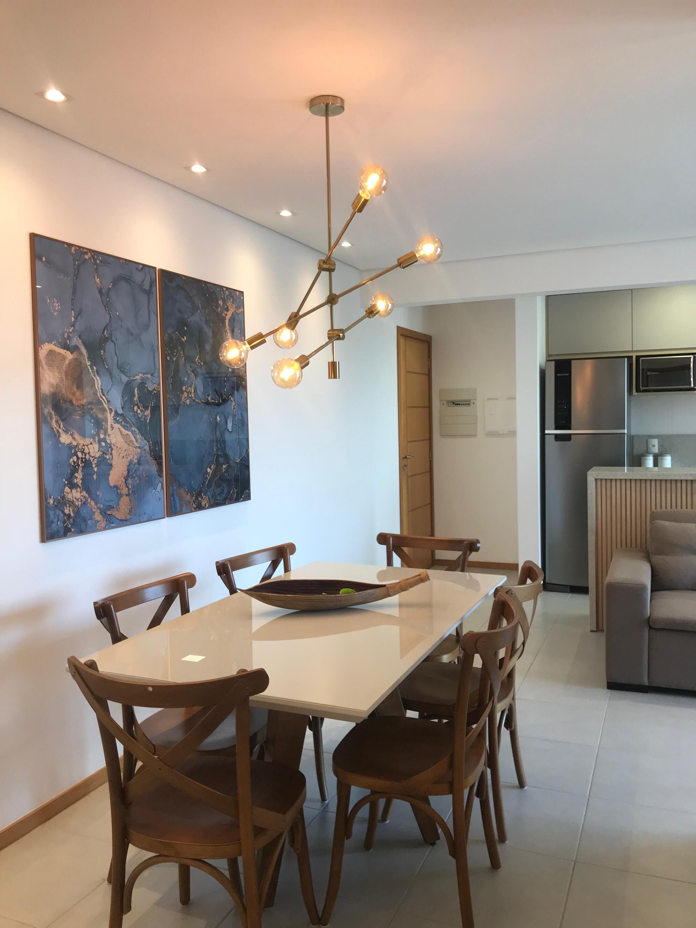 A modern dining area with a large table, wooden chairs, and a contemporary light fixture.