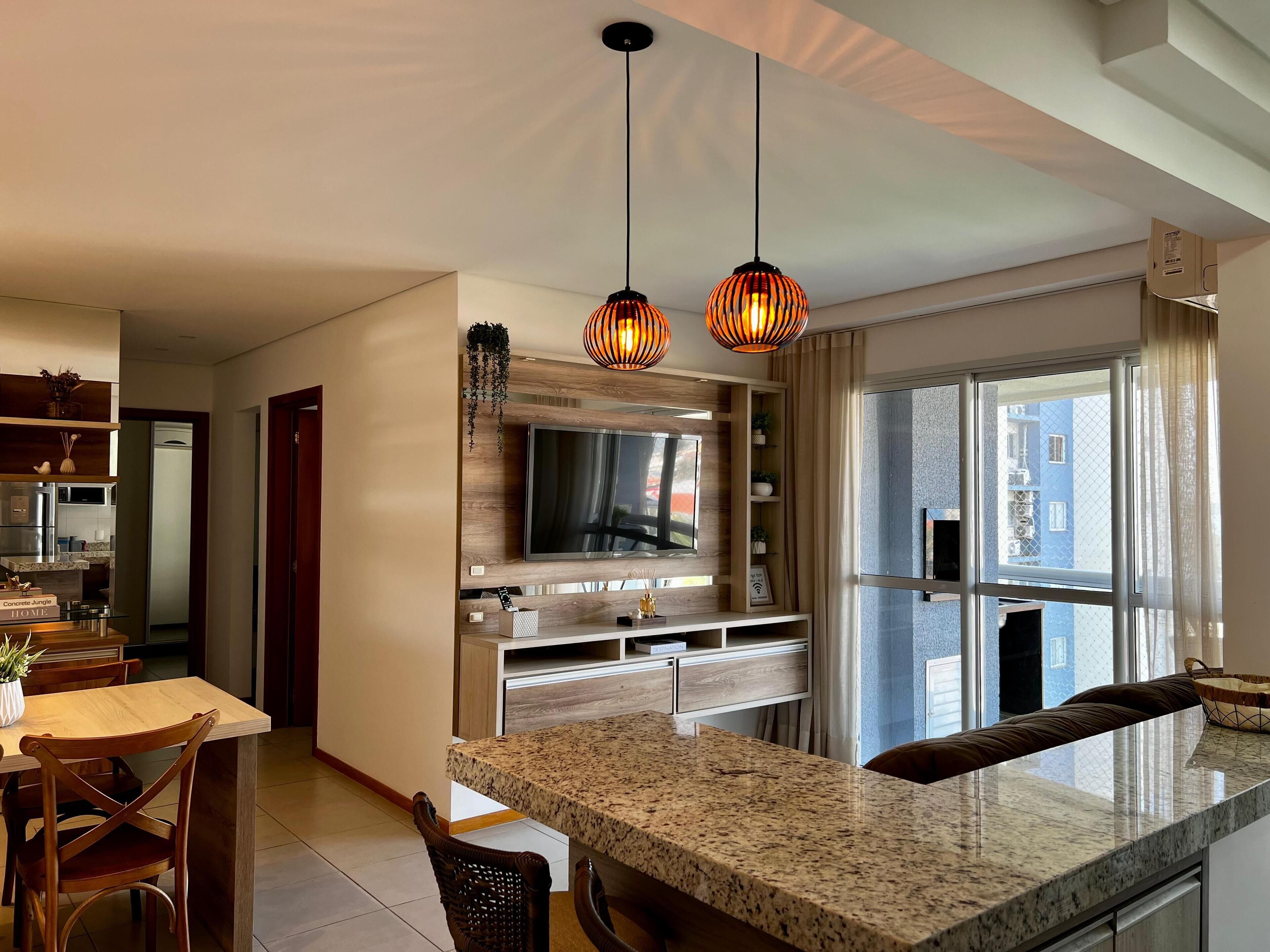A modern kitchen with granite countertops, a built-in oven, and a dining area with wooden chairs.