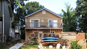 Uma casa de dois andares com varanda, entrada com calçada e área de estar externa.