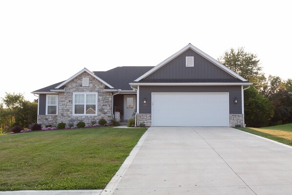 A two-story house with a stone facade, a garage, and a well-maintained lawn. - Safe Haven - Newer Home In A Quiet Neighborhood (Sugarcreek)