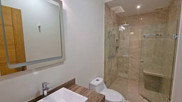 A modern bathroom with a glass-enclosed shower, a white sink, and a toilet.