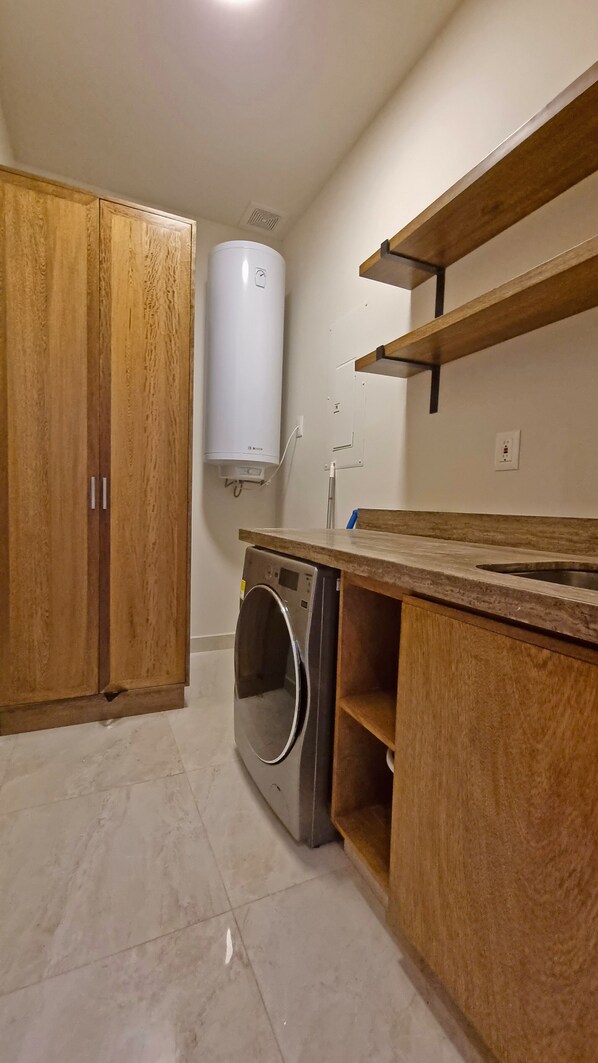 Une cuisine compacte avec des meubles en bois, un lave-linge encastré et un chauffe-eau.