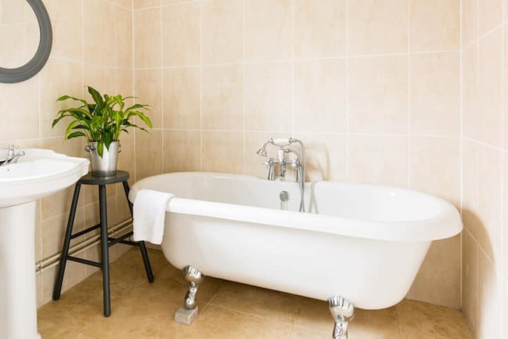A bathroom with a freestanding bathtub, a sink, and a potted plant.