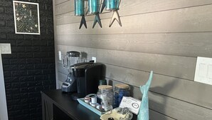 Un coin cuisine doté d’un plan de travail noir, d’une machine à café, de bocaux et d’une sculpture de poisson décorative.