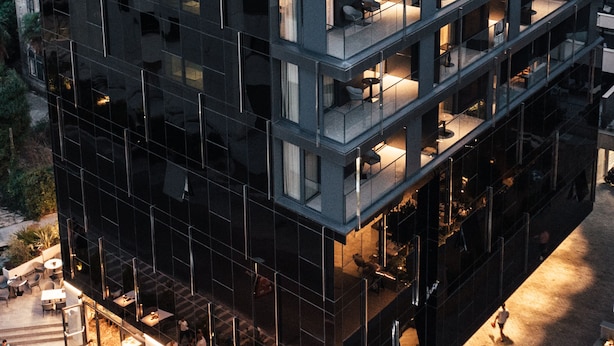 Ein modernes Hotel mit mehreren Balkonen, Sitzgelegenheiten im Freien und einer Dachterrasse.