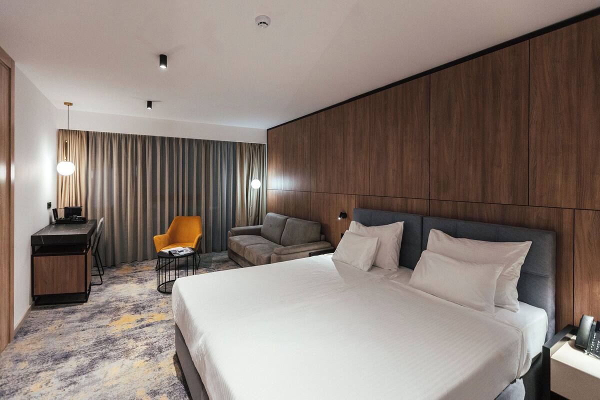 Ein modernes Hotelzimmer mit einem großen Bett, einem Schreibtisch, einem Stuhl und einem Sofa.